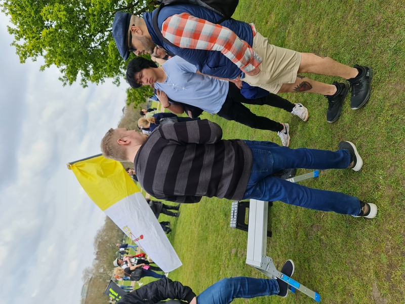 A group of three men, one holding a Vatican flag, another is visibly wearing a rosary.